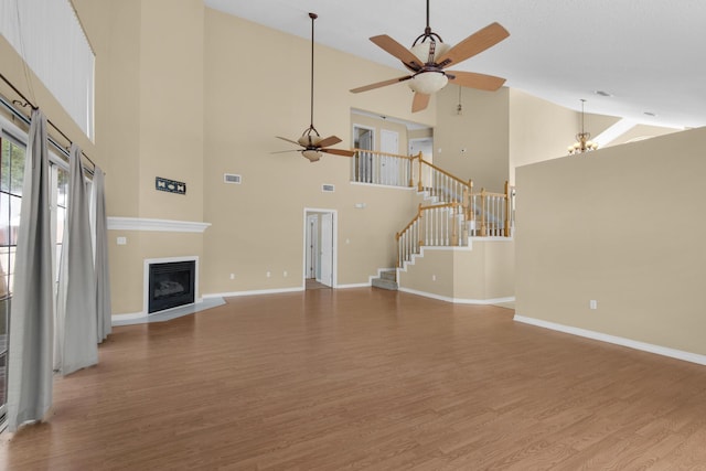 880 Brande Ct, Shalimar, FL 32579 - unfurnished living room with high vaulted ceiling, a ceiling fan, wood finished floors, stairs, and a fireplace with flush hearth