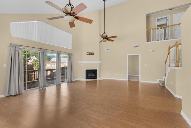 880 Brande Ct, Shalimar, FL 32579 - unfurnished living room featuring a ceiling fan, wood finished floors, baseboards, a towering ceiling, and stairs