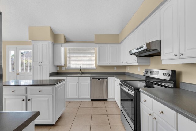 880 Brande Ct, Shalimar, FL 32579 - kitchen with stainless steel appliances, a sink, under cabinet range hood, dark countertops, and white cabinets