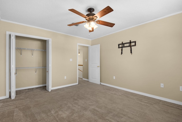 unfurnished bedroom featuring ornamental molding, carpet floors, ceiling fan, and a closet