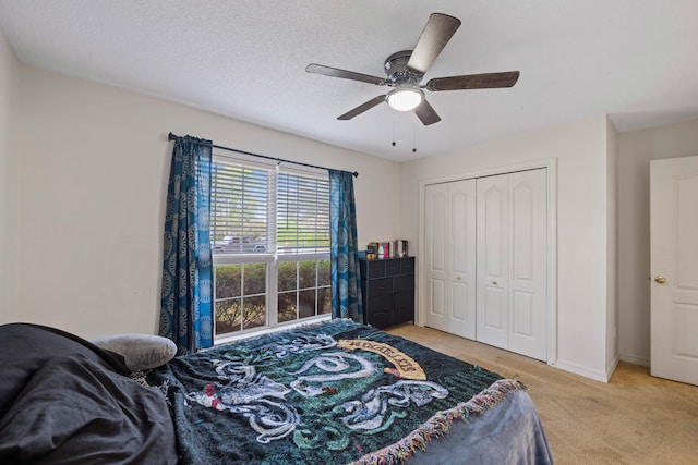 bedroom with ceiling fan, light colored carpet, a textured ceiling, and a closet