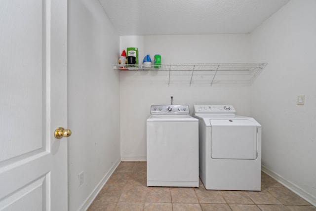 laundry area featuring independent washer and dryer, light tile patterned floors, and a textured ceiling