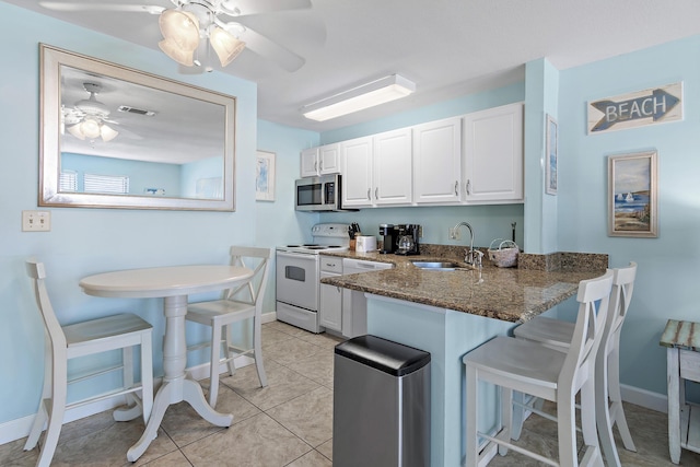 775 Gulf Shore Dr Unit 8112, Destin, FL 32541 - kitchen with white appliances, a kitchen breakfast bar, white cabinets, dark stone countertops, and ceiling fan