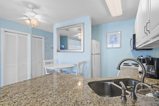 775 Gulf Shore Dr Unit 8112, Destin, FL 32541 - kitchen with freestanding refrigerator, light stone countertops, white cabinetry, and a ceiling fan