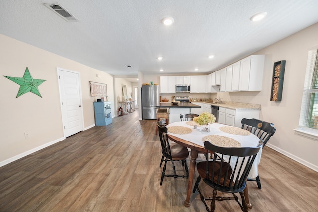 dining area with sink, hardwood / wood-style flooring, and a textured ceiling