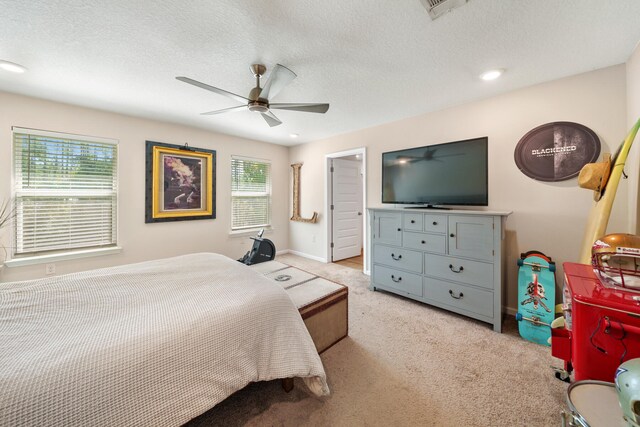 bedroom featuring ceiling fan, light colored carpet, and a textured ceiling