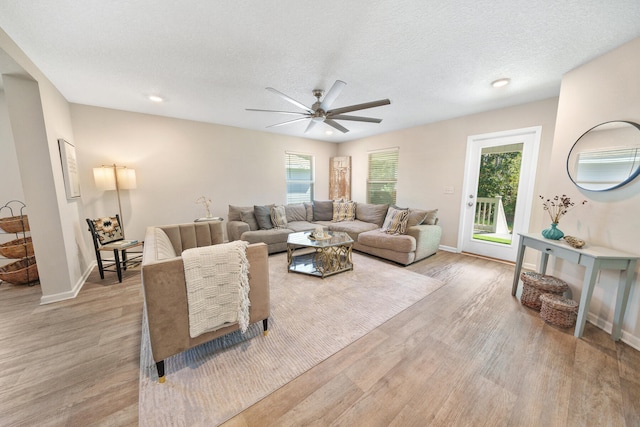 living room featuring ceiling fan, light hardwood / wood-style floors, a textured ceiling, and a healthy amount of sunlight