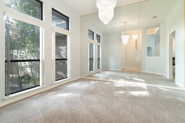 carpeted empty room with plenty of natural light and a notable chandelier