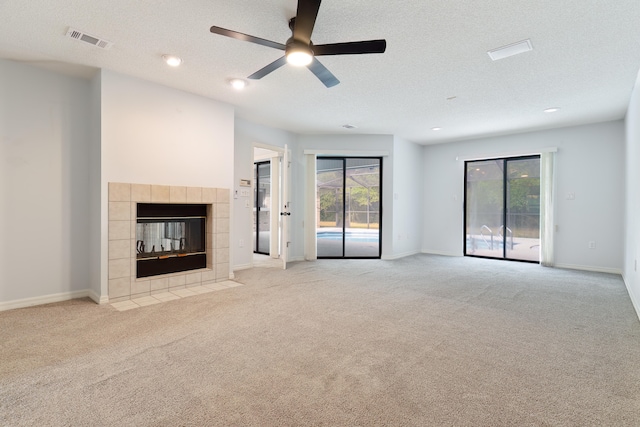 unfurnished living room featuring ceiling fan, light carpet, and a tiled fireplace