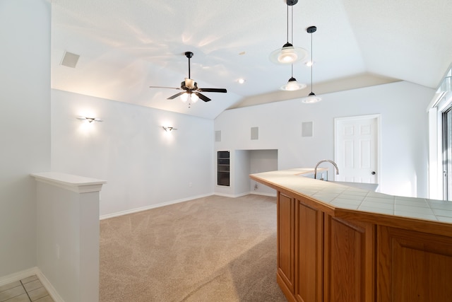 kitchen with tile counters, light colored carpet, decorative light fixtures, and vaulted ceiling