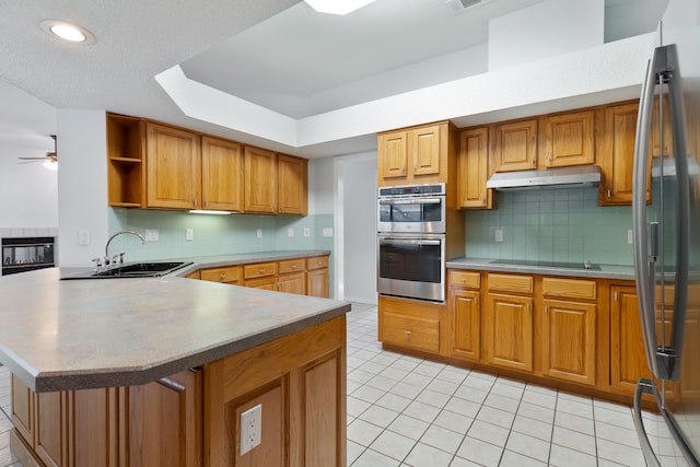 kitchen featuring stainless steel appliances, sink, backsplash, and kitchen peninsula