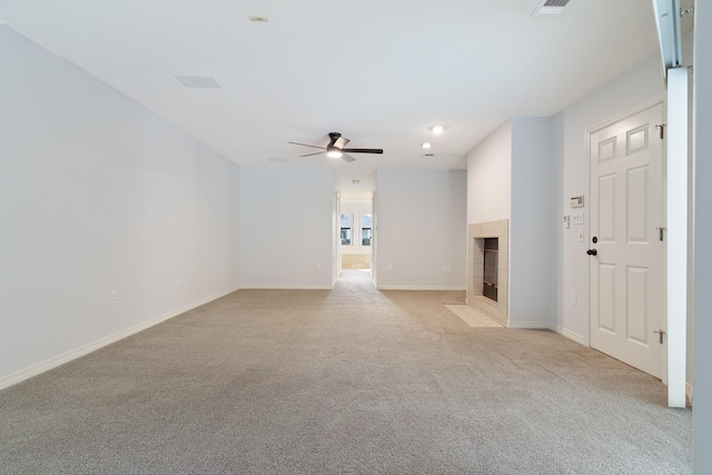 unfurnished living room with a tile fireplace, light carpet, and ceiling fan