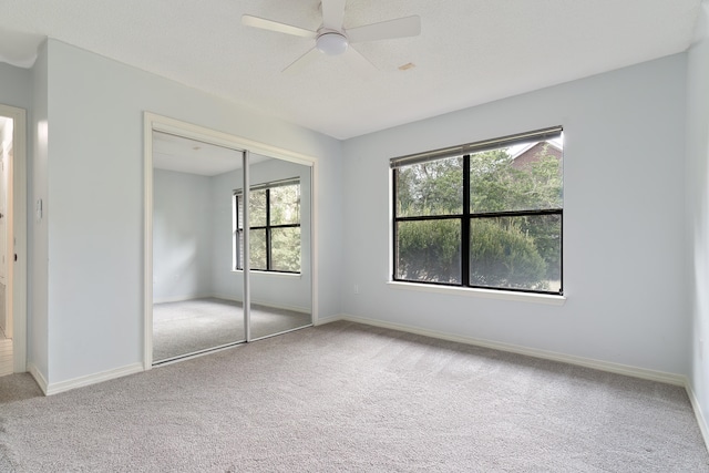 unfurnished bedroom with a closet, carpet flooring, and ceiling fan