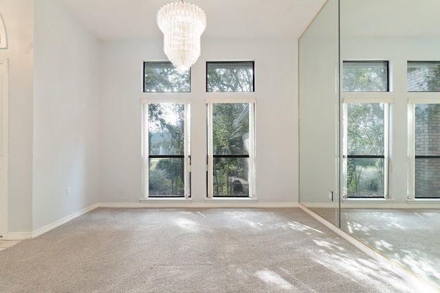 carpeted empty room with a chandelier