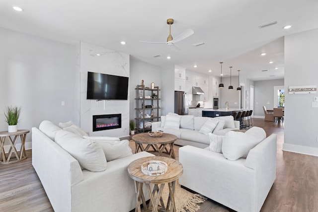 living room with ceiling fan, light hardwood / wood-style flooring, and a fireplace