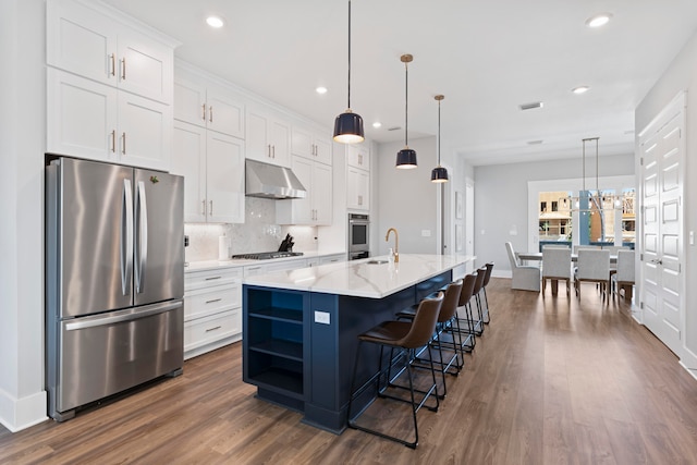 kitchen with ventilation hood, a kitchen island with sink, stainless steel appliances, and white cabinets