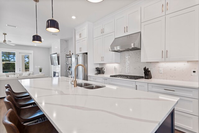 kitchen with a kitchen breakfast bar, tasteful backsplash, white cabinets, pendant lighting, and sink