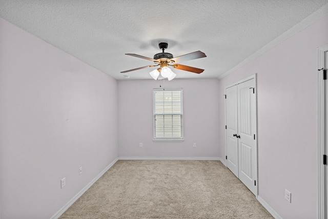 spare room featuring light carpet, a textured ceiling, and ceiling fan