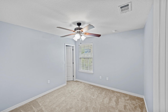 empty room with a textured ceiling, light colored carpet, and ceiling fan