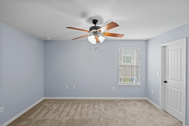 spare room with a textured ceiling, light colored carpet, and ceiling fan