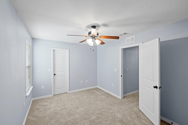 unfurnished bedroom featuring a textured ceiling, light colored carpet, and ceiling fan