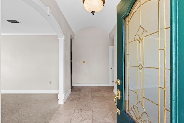 foyer entrance featuring light carpet, vaulted ceiling, and crown molding