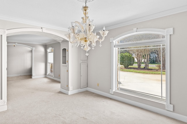 unfurnished dining area with a chandelier, crown molding, plenty of natural light, and light colored carpet