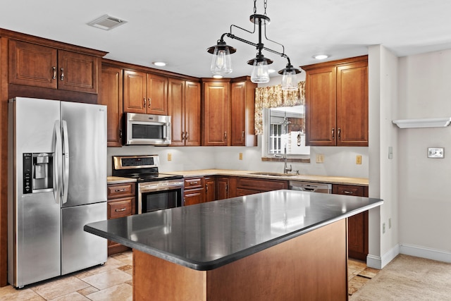 kitchen with appliances with stainless steel finishes, a center island, decorative light fixtures, and sink