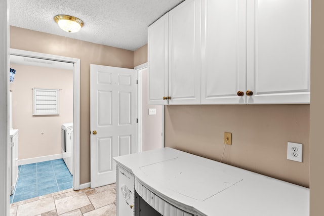 clothes washing area with cabinets, a textured ceiling, and separate washer and dryer