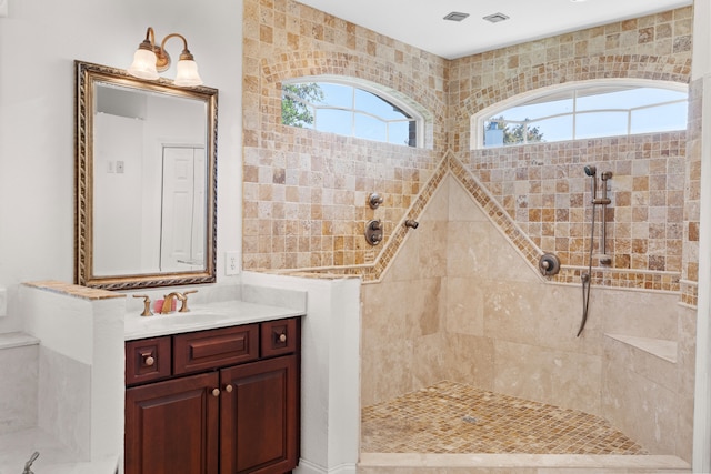 bathroom with tiled shower and vanity