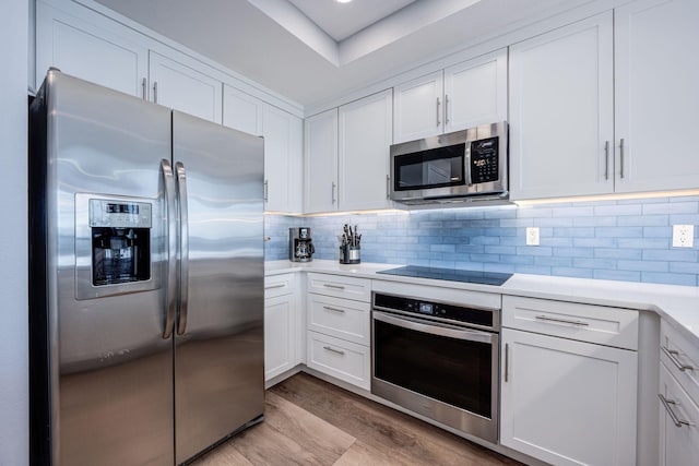 8477 Gulf Blvd Unit 1001, Navarre, FL 32566 - kitchen with appliances with stainless steel finishes, light countertops, white cabinetry, light wood-type flooring, and tasteful backsplash