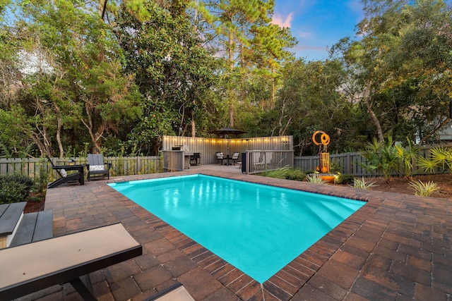 pool at dusk with a patio area