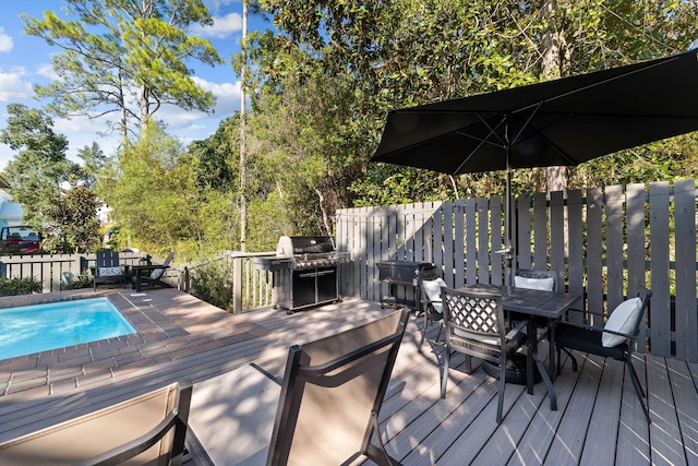 wooden deck featuring grilling area and a fenced in pool