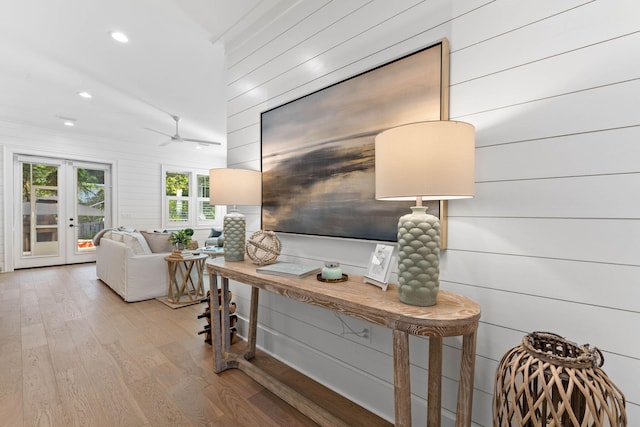 interior space featuring ceiling fan, light wood-type flooring, wood walls, and french doors