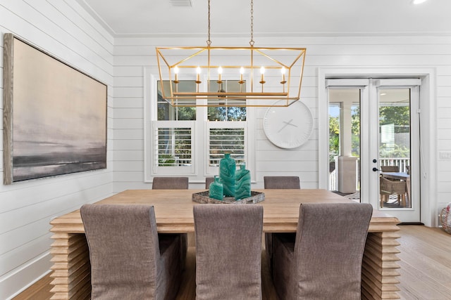 dining space featuring hardwood / wood-style flooring, wooden walls, an inviting chandelier, and a wealth of natural light