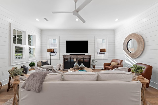 living room with wood walls, ceiling fan, and hardwood / wood-style flooring