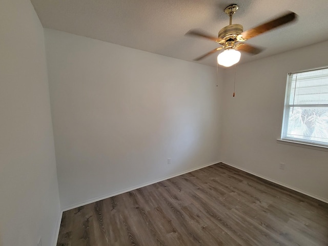 unfurnished room with dark wood-style flooring, ceiling fan, and baseboards