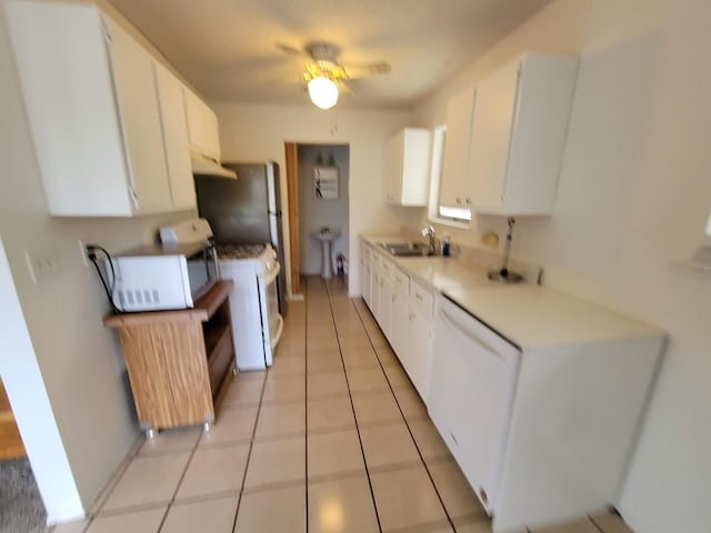 kitchen with white cabinets, a sink, white appliances, light countertops, and light tile patterned floors
