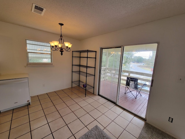 unfurnished dining area with light tile patterned floors, a textured ceiling, a chandelier, and visible vents
