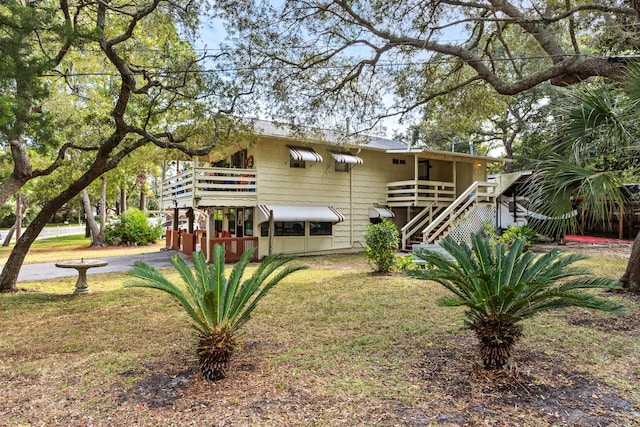 rear view of house with a yard, stairway, and a deck