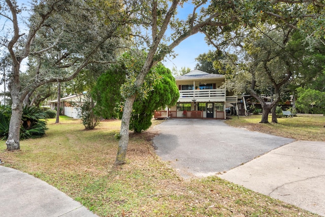 raised beach house with a carport, a front lawn, driveway, and stairway