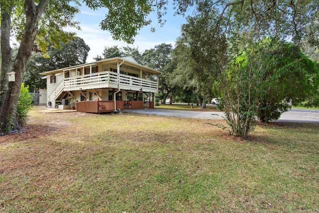 back of house with a lawn, a deck, a hot tub, and aphalt driveway
