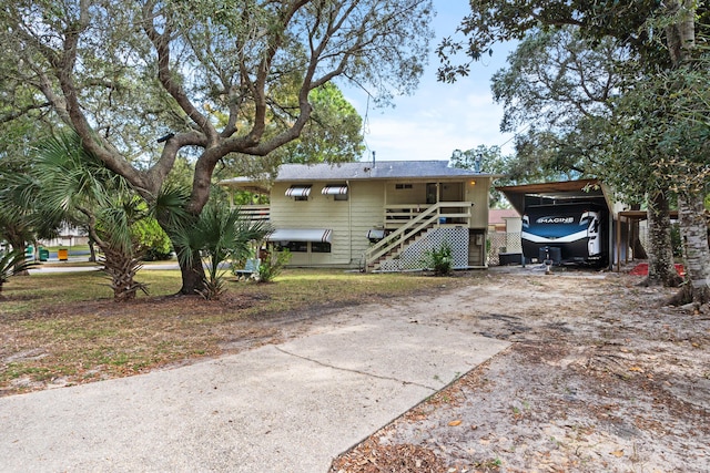 view of front of house featuring driveway, stairs, and a carport