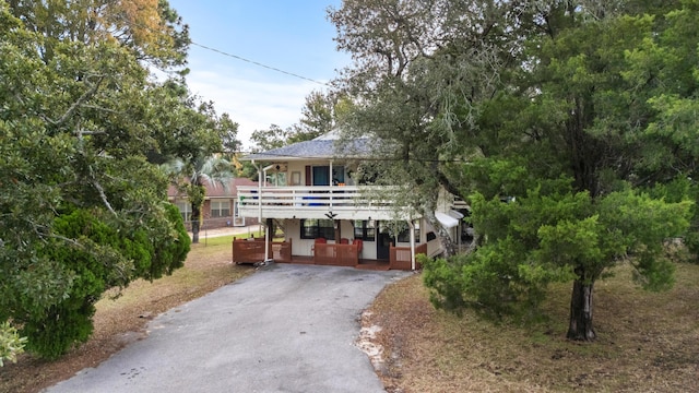 raised beach house featuring covered porch and aphalt driveway