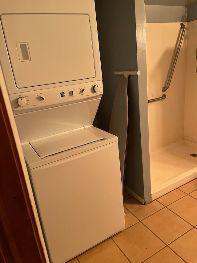 washroom with stacked washing maching and dryer and light tile patterned flooring