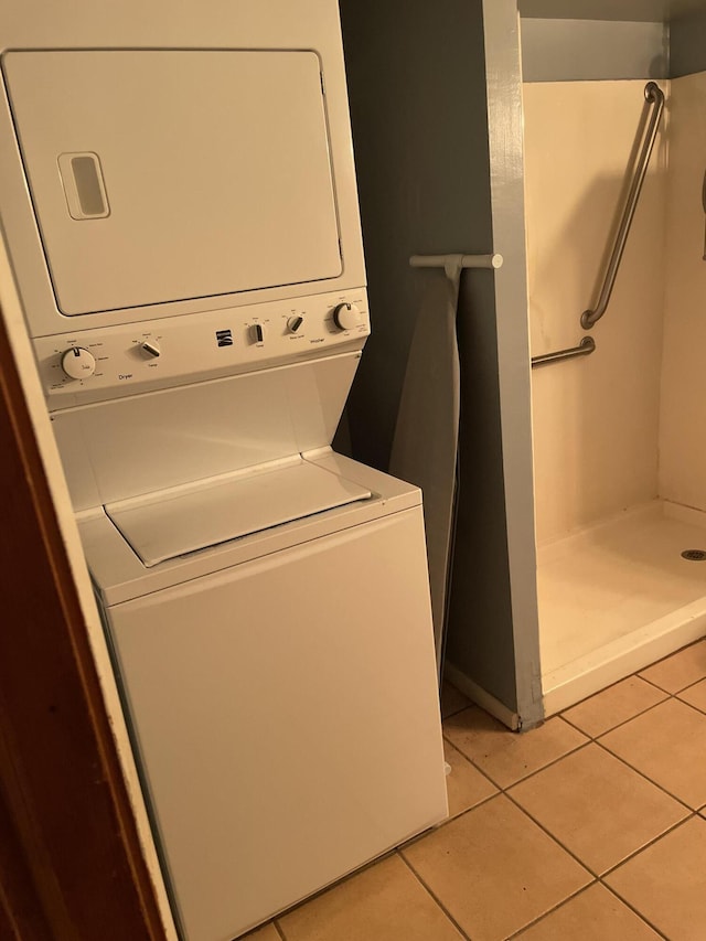 clothes washing area featuring laundry area, stacked washer and clothes dryer, and light tile patterned floors