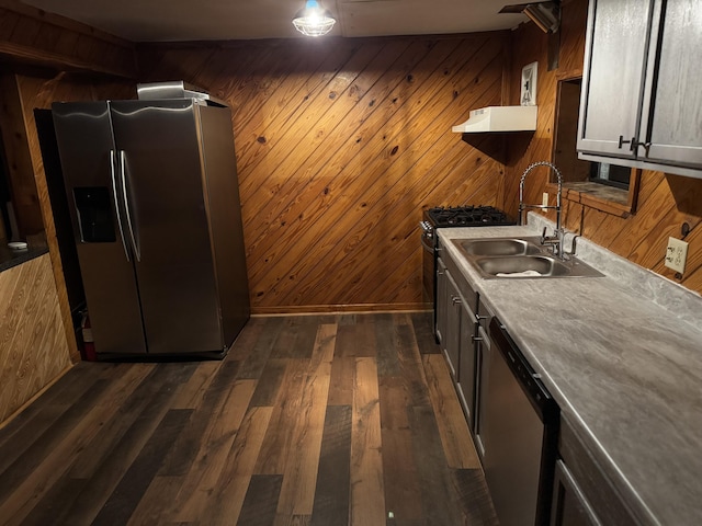 kitchen featuring appliances with stainless steel finishes, sink, dark wood-type flooring, and wood walls