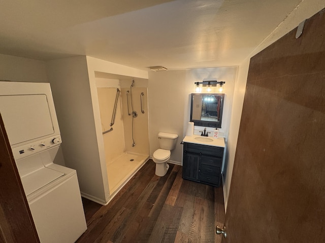 bathroom featuring toilet, a shower, vanity, hardwood / wood-style flooring, and stacked washing maching and dryer