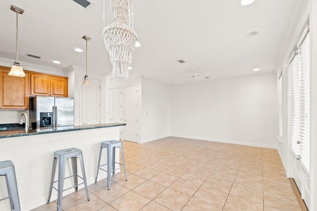 kitchen featuring ornamental molding, pendant lighting, stainless steel fridge, and a breakfast bar