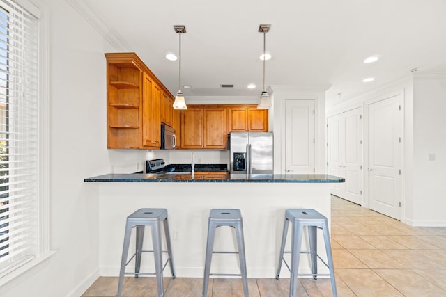 kitchen featuring kitchen peninsula, a kitchen breakfast bar, pendant lighting, and appliances with stainless steel finishes